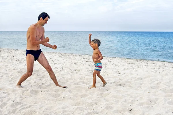 son and dad are fighting, dad and son play sports on the sanddad and son engaged in karate