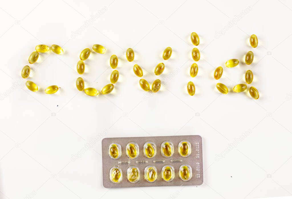 covid -19 laid out in the form of capsules with vitamin D with a package of tablets with a blister on a white background