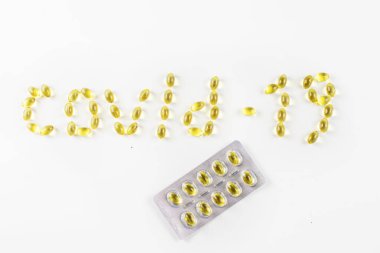 covid -19 beyaz bir zemin üzerinde bir kabarcık içinde tablet ambalajı ile D vitamini içeren kapsüller şeklinde serildi