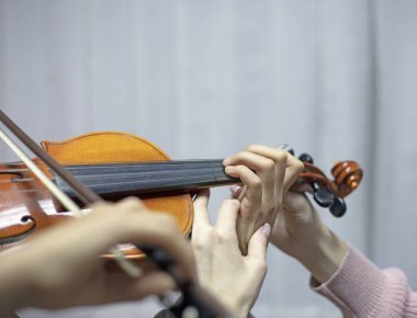 Keman çalarken çocukların ellerini yerleştirerek öğretmene elini doğru şekilde tutmasında yardımcı oluyor.