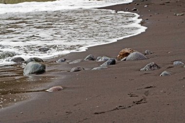 Tenerife adasında deniz çekildiğinde kumlu kumsalda çakıl taşları,