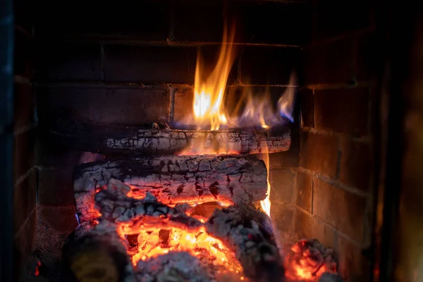 石の暖炉の横型に積み上げられた薪に火の炎 — ストック写真