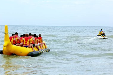 Bir grup insan su bisikleti ile şişme köpekbalığı sürüyorlar.