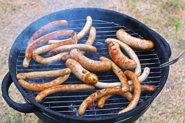 Kızarmış sosis ve sosis ızgaranın üstünde kuru otların üstünde.