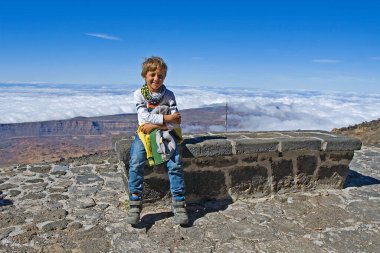 Mutlu çocuk, Tenerife Adası 'ndaki Teide volkanı yakınlarındaki Altavista kamp alanında tek gecelik tezgahta oturuyor.