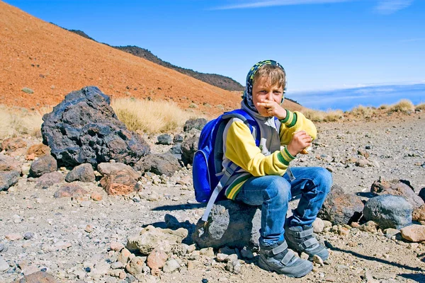 happy young mountain hiker on a ramp before climbing to the Teide volcano, eating a sandwich, mountain landscape, Spain, the path to yourself