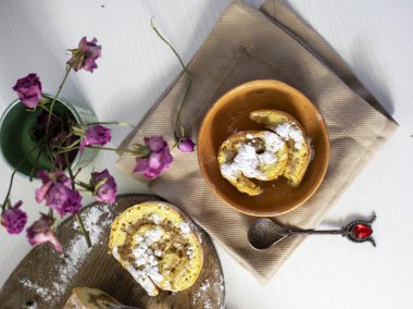 Yeni pişmiş iki parça elmalı rulo peçetede ekmek kırıntıları ve bir gül, aile kahvaltısı, yatay