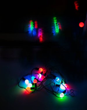 Koyu arkaplanda kalp şeklinde rengarenk çelenkler ve penceredeki yansıma dikey.