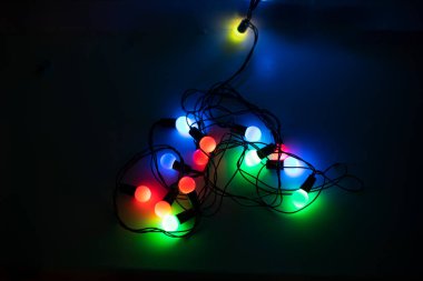 multicolored garlands in the form of a heart on a dark background, horizontal