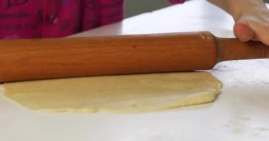 Çocukların elleri hamuru masaya oklavayla yuvarlıyor.