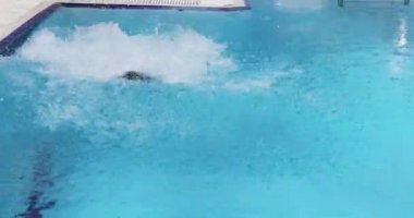 Mutlu çocuk havuza atlıyor ve suyun altında yüzüyor.