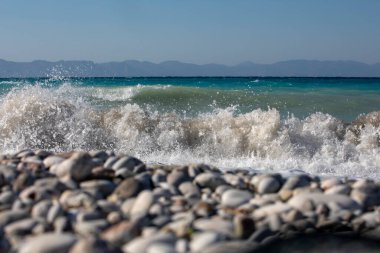 Sahilde çakıl taşlı köpüklü deniz dalgaları