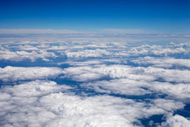 Gökyüzü, yerden görünen gök gürültülü beyaz bulutlarla, yatay, uçak penceresinden.