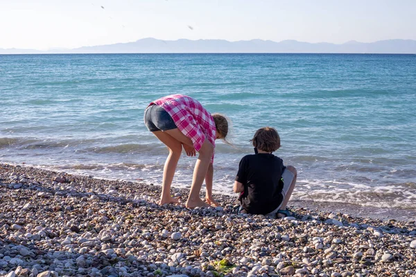 happy boy and girls throw stones into the sea, family vacation, Greece