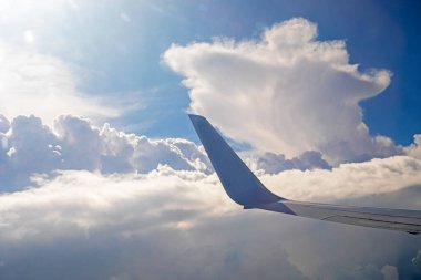 Uçağın penceresinden güneş ışınları boyunca bulutlar uçakla, yatay olarak seyahat eder.