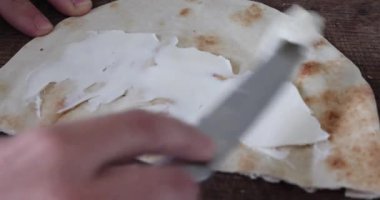 İnce taze bir pidenin üzerine bıçakla mascarpone dilimleri serpiştir ve kes.