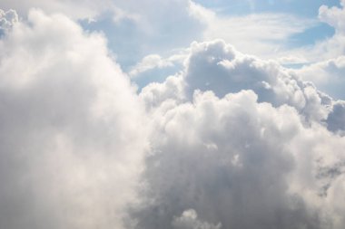 Beyaz fırtına bulutları yatay bir uçak penceresinden güneş ışınlarına doğru ilerliyor.