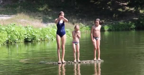 在温暖的天气里 三个孩子以不同的方式从河里的桥上跳入水中 — 图库视频影像