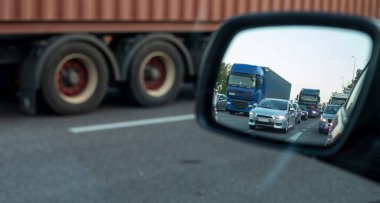 Bir arabanın yan aynasında akşam trafiği sıkışık, yol tamiri sırasında, trafik yoğunluğu şehir caddesinde.