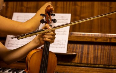 Genç bir kemancıyı kemanın üzerine koyup piyanonun yanında notlar arıyor, goizontal