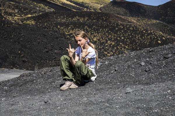 Teenage brother and sister on the peaks of Mount Etna during the day. Active school holidays.