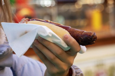 Bir sokak fuarında lezzetli, sıcak Alman sosisi yemek.