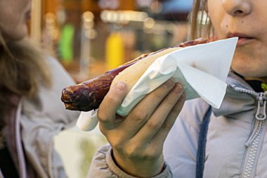 Bir sokak fuarında lezzetli, sıcak Alman sosisi yemek.