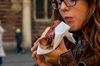 Mutlu genç kız bir tatil fuarında Alman sosisi yiyor..