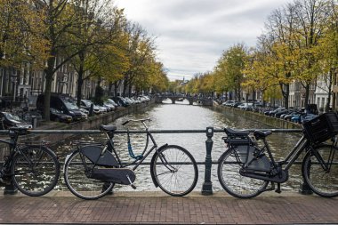 Gün boyunca Amsterdam 'da bir kanal boyunca bisiklet parkı.