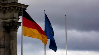 Berlin 'de bulutlu bir günde Alman parlamentosunda Alman ve NATO bayrakları.