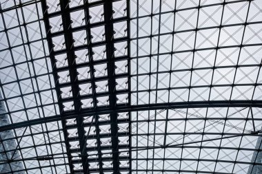 Modern bir iç mekan, cam çatılı bir tren istasyonu.