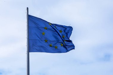 NATO bayrağı rüzgarlı bir günde bulutlu bir gökyüzüne karşı. Siyasi oyunlar.