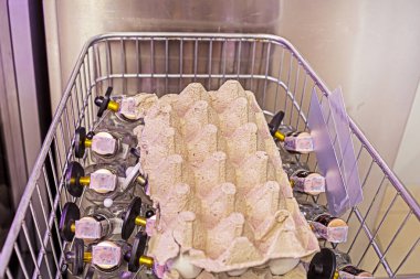 Metal bir market arabasında yumurtaları olan karton bir kap.