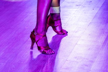 Latin dansçı kız dans pistinde dans ayakkabısı giyiyor.