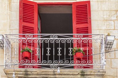Malta 'da kırmızı panjurları ve kırmızı saksıları olan demir işlemeli balkon. Avrupa 'da seyahat