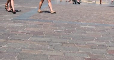 Sıcak bir günde, turistlerin ayakları terliklerle meydanda yürür. Avrupa 'da seyahat.