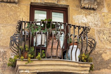Çiçek saksılarıyla süslenmiş antika dövmeli demir balkon. İtalya 'da seyahat
