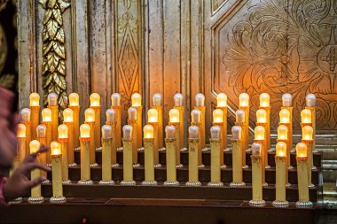 Bir azizin yanındaki elektronik mumu yakmak için bozuk para atıyorsun.