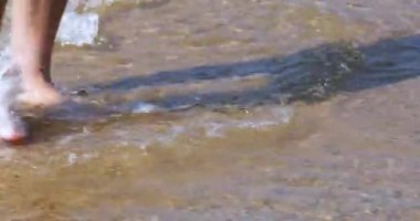 Adam deniz kıyısında yalınayak yürüyor. Kumun üzerinde yürümek yararlıdır. Ortak bakım.