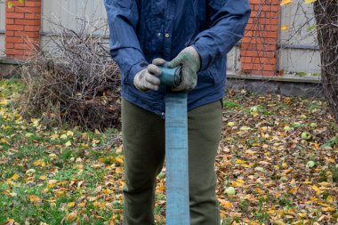 Bir adam hortumu büker ve sıvıyı serbest bırakır. Bahçe gübresi.