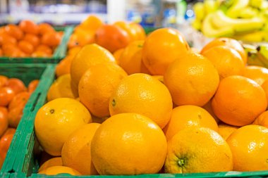 Süpermarkette yeşil plastik kaplarda portakal ve muz var.