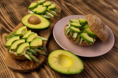 Sağlıklı vejetaryen organik kahvaltı sandviçi kuşkonmaz, avokado, salatalık, tam tahıllı çöreğin üzerine yumuşak peynir. Tahta, tahtayı kapat.