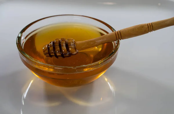 Glass bowl plate with honey wood spoon, dipper, white background, copy space — Stock Photo, Image