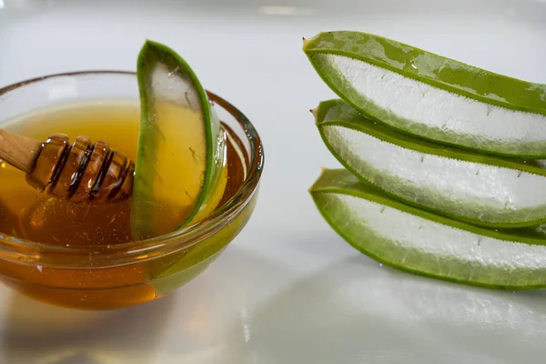 Aloe Vera irisan dengan jus dan madu sendok kayu pada piring putih, perawatan kulit spa — Stok Foto