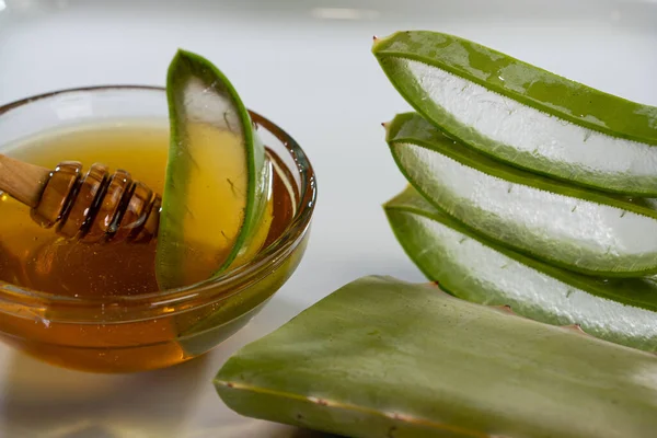 Aloe Vera slices with juice and honey wood spoon on white plate, skin care spa — Stock Photo, Image