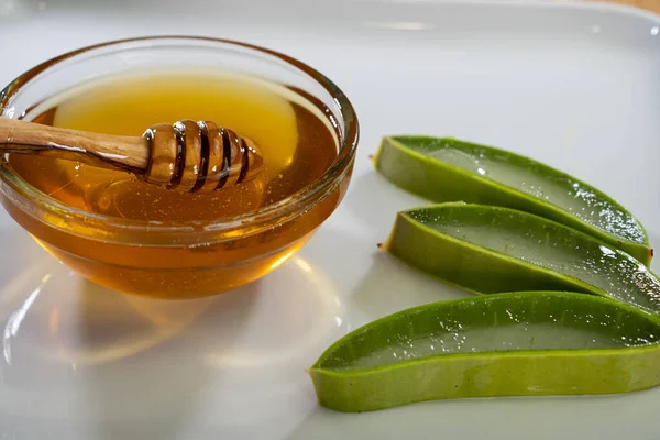 Aloe Vera slices with juice and honey wood spoon on white plate, skin care spa — Stock Photo, Image