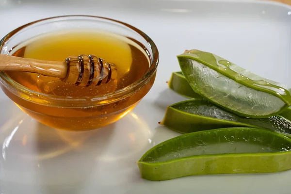Tranches d'Aloe Vera avec jus et cuillère en bois de miel sur plaque blanche, spa de soins de la peau — Photo