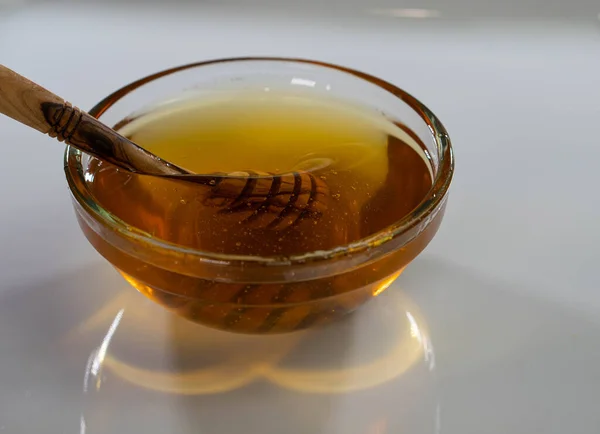 Glass bowl plate with honey wood spoon, dipper, white background, copy space — Stock Photo, Image