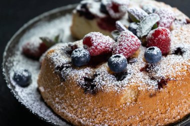 Pudra şekerli meyveli turta ve beyaz tabakta tarçın, ev yapımı yakın plan.