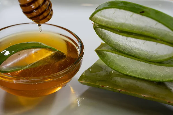 Aloe Vera slices with juice and honey wood spoon on white plate, skin care spa — Stock Photo, Image